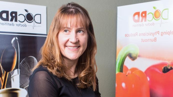 Michelle Mudge Riley sits between two informational posters describing nutrition programs