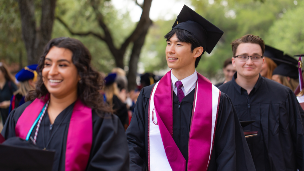 graduates from the Class of 2022 walk by their professors after the Commencement ceremony