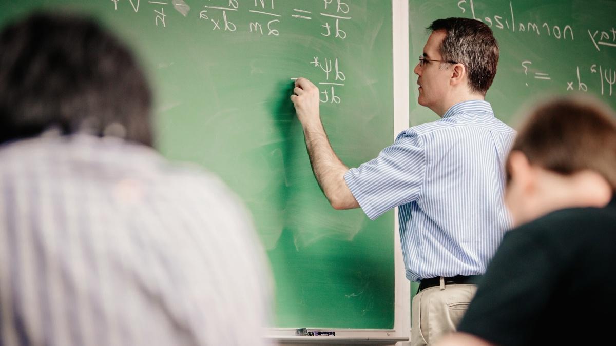 Professor at the chalkboard writing out equations